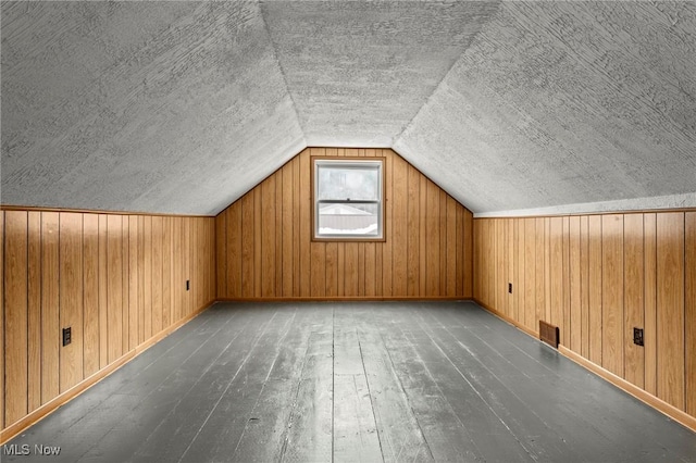 bonus room featuring vaulted ceiling, dark hardwood / wood-style floors, a textured ceiling, and wood walls