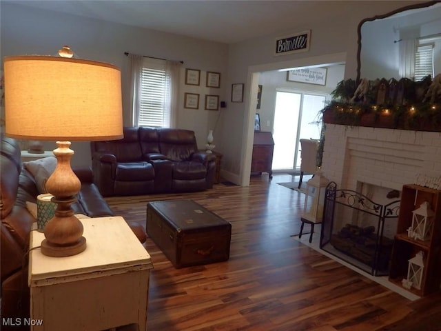 living room featuring dark hardwood / wood-style flooring and a brick fireplace