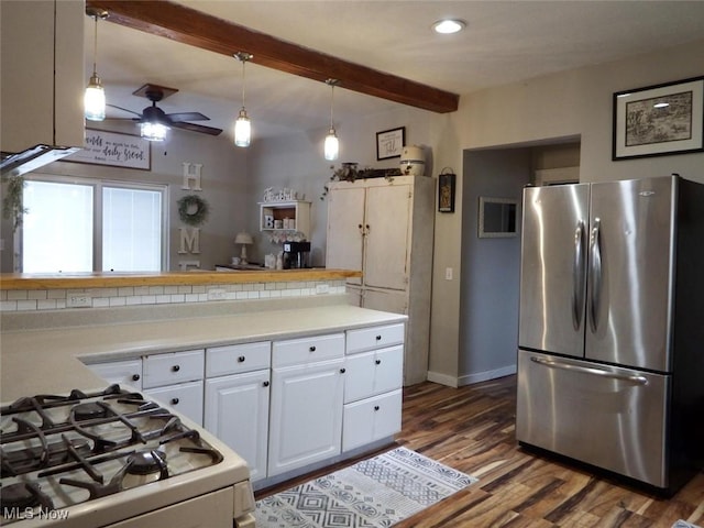 kitchen featuring gas range gas stove, white cabinetry, hanging light fixtures, stainless steel refrigerator, and beam ceiling