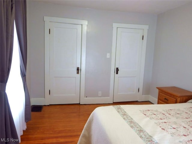 bedroom featuring light wood finished floors, visible vents, and baseboards