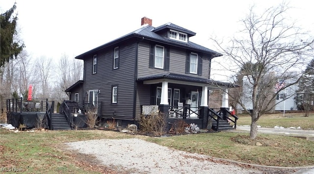 american foursquare style home featuring a porch, a chimney, and a front yard