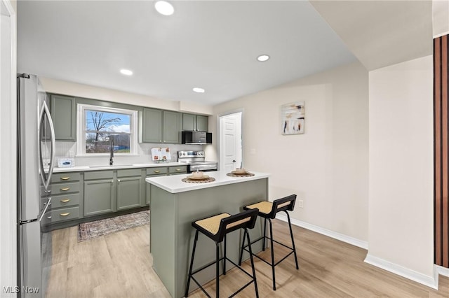 kitchen with sink, a breakfast bar area, a center island, stainless steel appliances, and light wood-type flooring