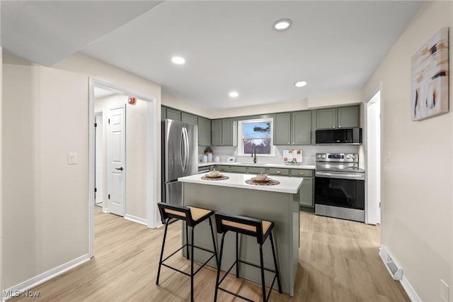 kitchen with sink, light wood-type flooring, a kitchen breakfast bar, a kitchen island, and stainless steel appliances