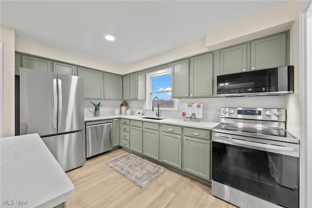 kitchen featuring stainless steel appliances, sink, light hardwood / wood-style flooring, and green cabinetry