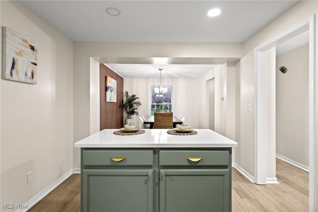 kitchen featuring green cabinetry, hanging light fixtures, a kitchen island, and light wood-type flooring