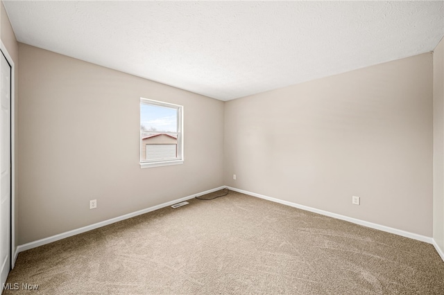 empty room with a textured ceiling and carpet flooring