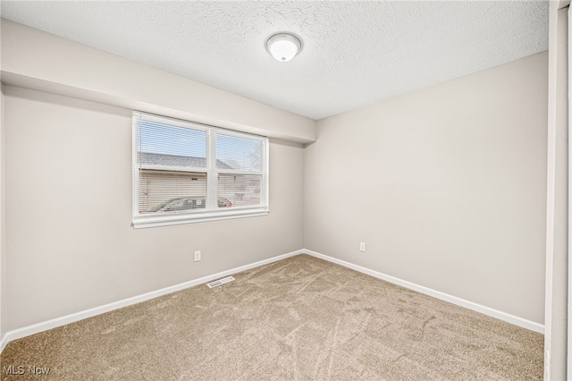 unfurnished room with light carpet and a textured ceiling