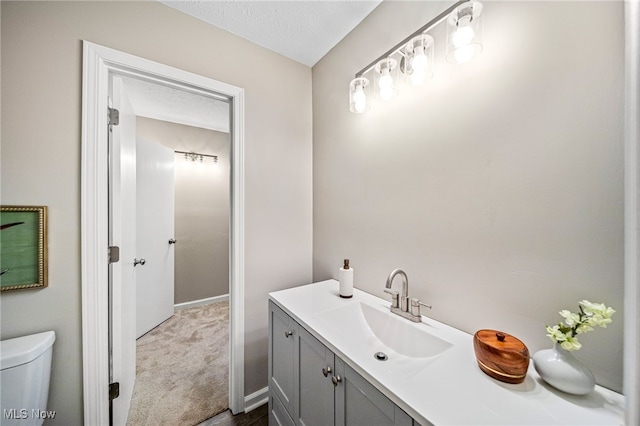 bathroom with vanity, toilet, and a textured ceiling