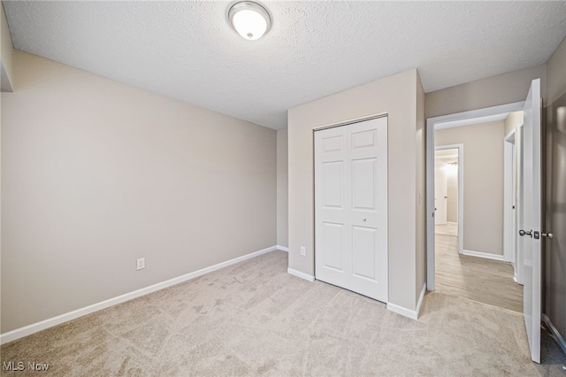 unfurnished bedroom featuring light colored carpet, a textured ceiling, and a closet