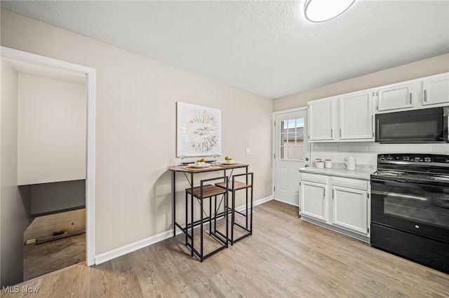 kitchen featuring white cabinetry, light wood-type flooring, decorative backsplash, black appliances, and a textured ceiling