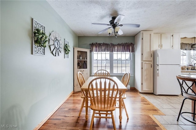 24886 Sherman St, Homeworth, OH 44634 - dining space with a ceiling fan, a textured ceiling, baseboards, and light wood finished floors