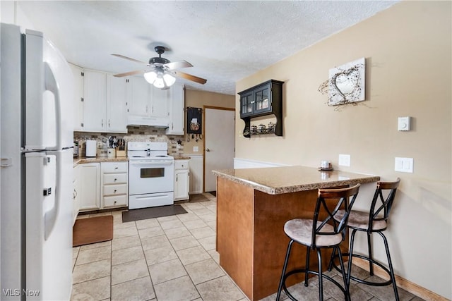 24886 Sherman St, Homeworth, OH 44634 - kitchen featuring a peninsula, white appliances, a breakfast bar, light countertops, and under cabinet range hood