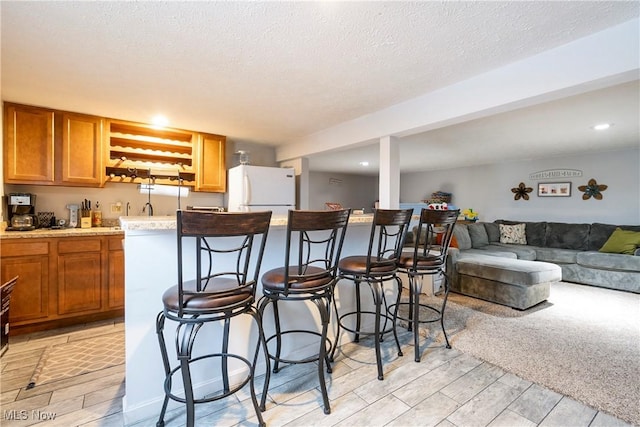 24886 Sherman St, Homeworth, OH 44634 - kitchen with brown cabinets, light countertops, freestanding refrigerator, open floor plan, and a kitchen bar