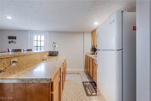 24886 Sherman St, Homeworth, OH 44634 - kitchen featuring recessed lighting, freestanding refrigerator, a textured ceiling, and brown cabinets