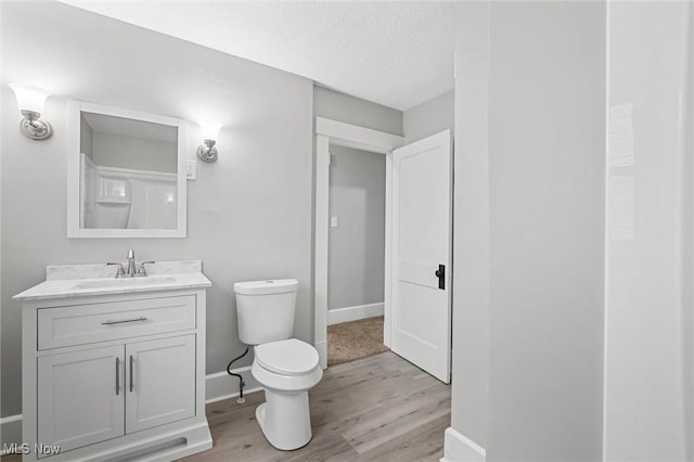 bathroom featuring hardwood / wood-style flooring, vanity, toilet, and a textured ceiling