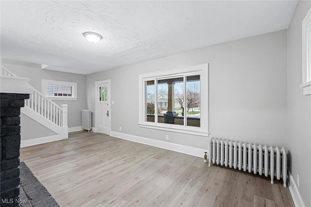 foyer entrance with radiator, light hardwood / wood-style flooring, and a textured ceiling