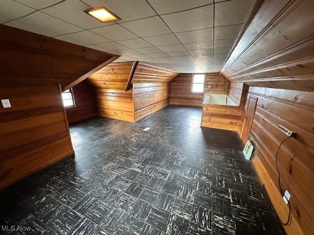 additional living space featuring lofted ceiling and wood walls