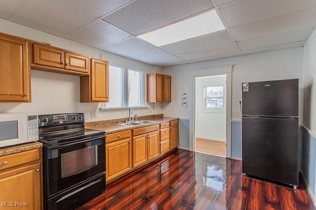 kitchen with sink, a paneled ceiling, black appliances, and dark hardwood / wood-style floors