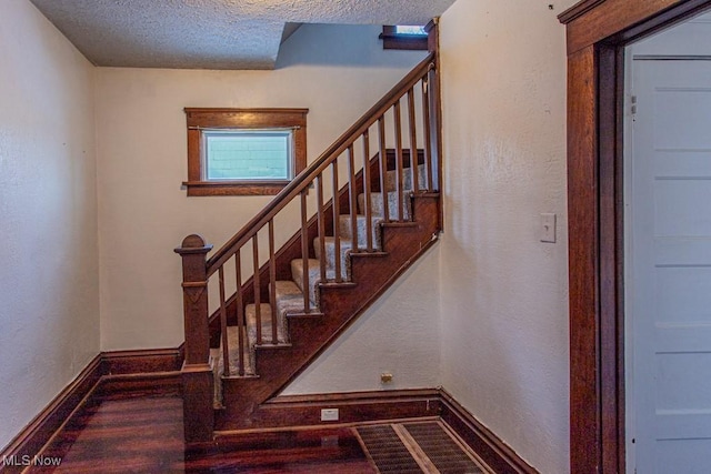 stairway featuring hardwood / wood-style flooring and a textured ceiling