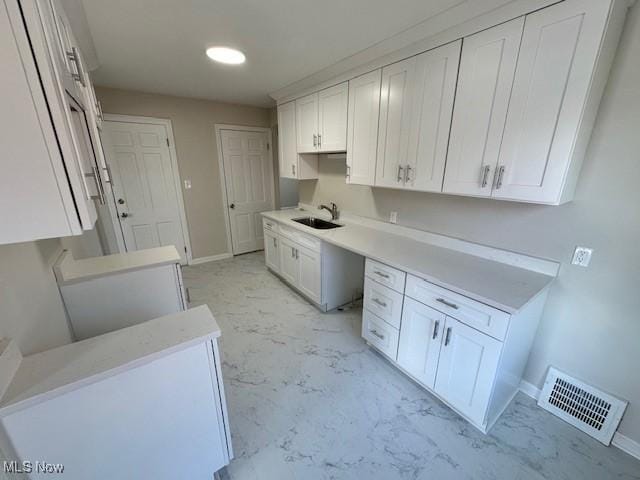 kitchen with white cabinetry, sink, and built in desk