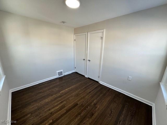 unfurnished room with dark wood-type flooring