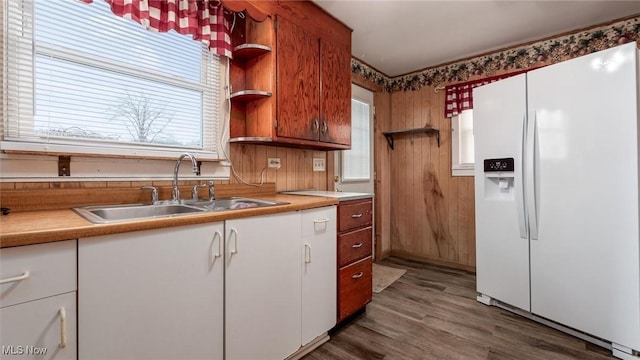 kitchen with sink, wood-type flooring, white refrigerator with ice dispenser, and white cabinets