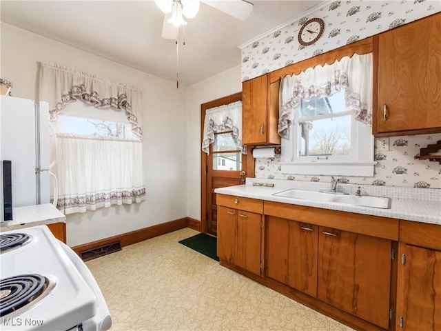 kitchen with sink, white appliances, ceiling fan, and backsplash