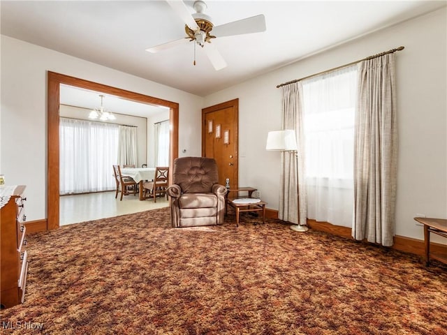 living area with dark carpet and ceiling fan with notable chandelier