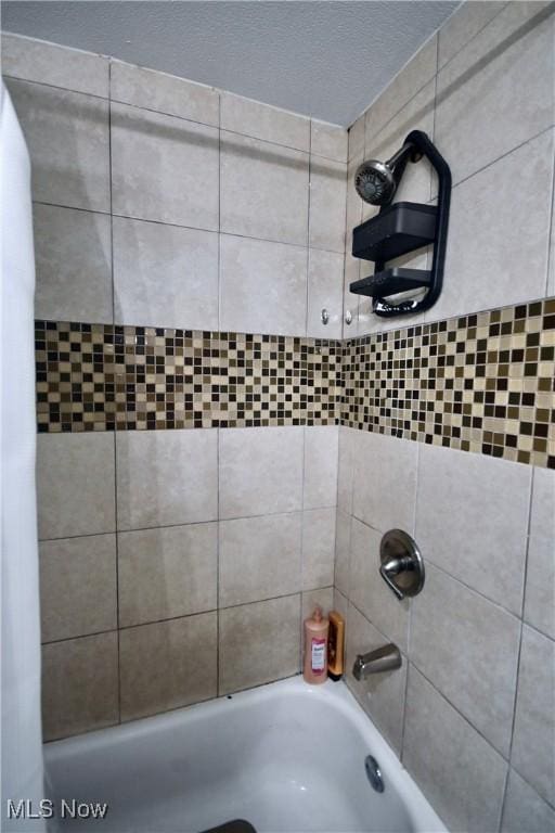 bathroom with a textured ceiling and shower / bath combo