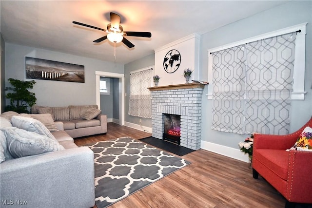 living room with a brick fireplace, dark hardwood / wood-style floors, and ceiling fan