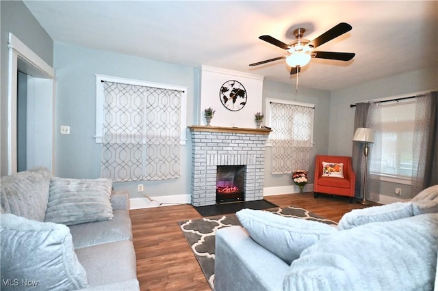 living room with dark wood-type flooring, ceiling fan, and a fireplace