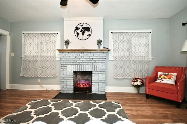 sitting room with wood-type flooring, a brick fireplace, and ceiling fan