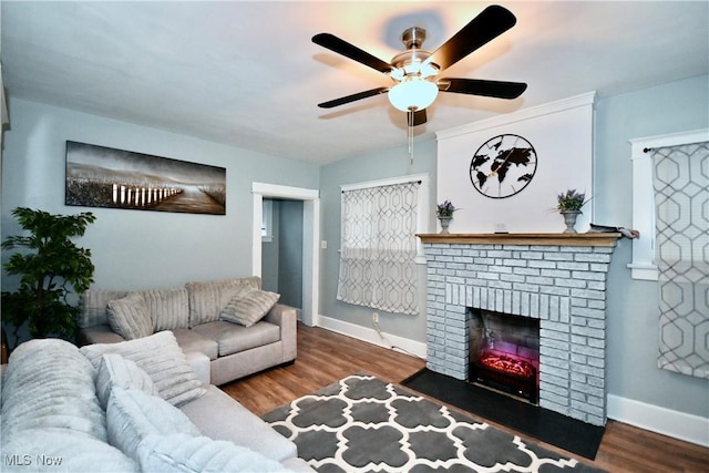 living room featuring ceiling fan, wood-type flooring, and a brick fireplace