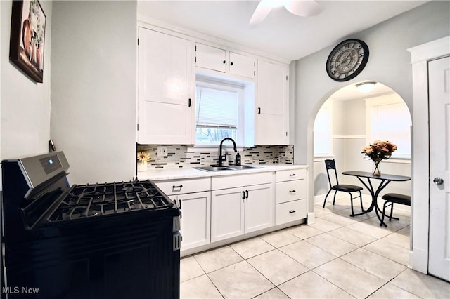 kitchen with sink, light tile patterned floors, white cabinetry, tasteful backsplash, and gas range