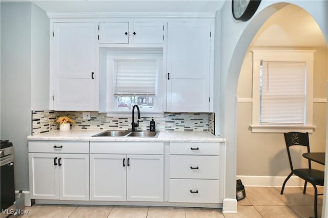 kitchen with sink, light tile patterned floors, white cabinets, and backsplash