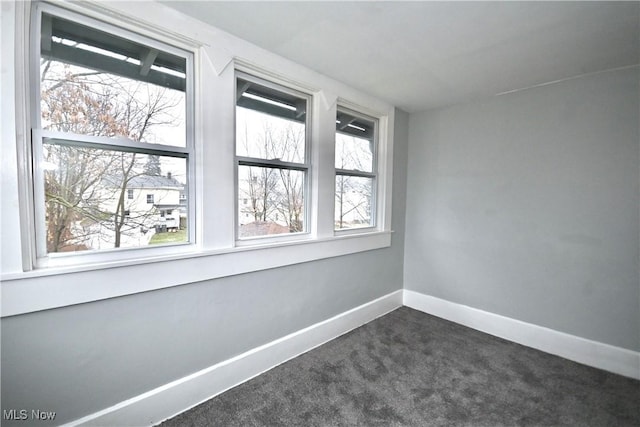 unfurnished room featuring dark colored carpet