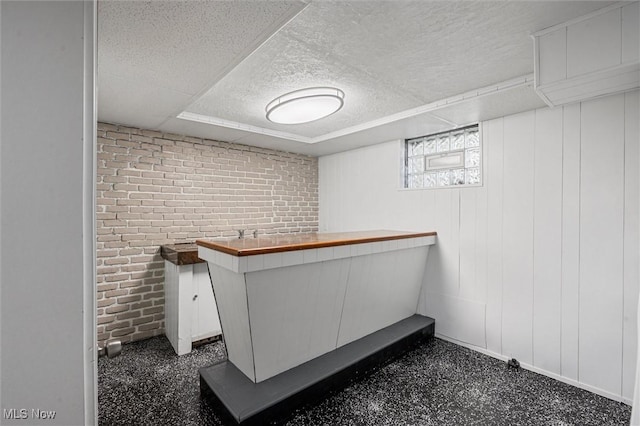 interior space featuring indoor bar, a textured ceiling, and brick wall