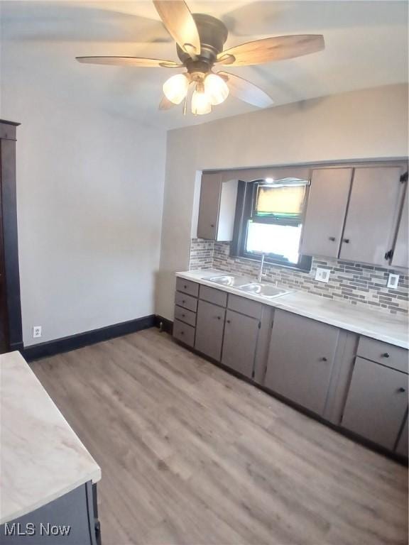 kitchen with gray cabinets, sink, backsplash, and light wood-type flooring