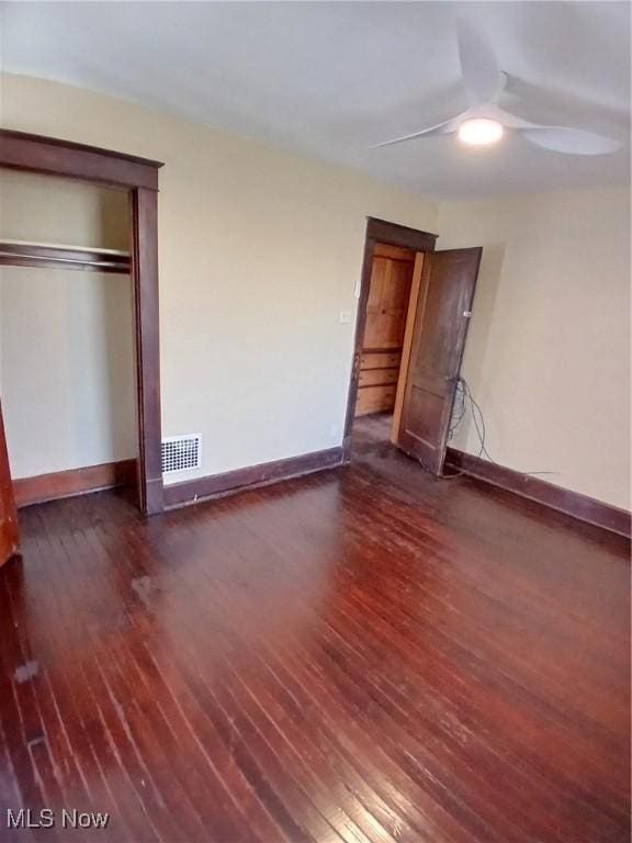 unfurnished bedroom with ceiling fan, dark hardwood / wood-style floors, and a closet