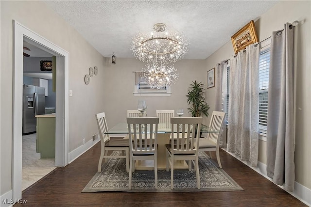 dining area featuring dark wood-type flooring, a textured ceiling, and a notable chandelier