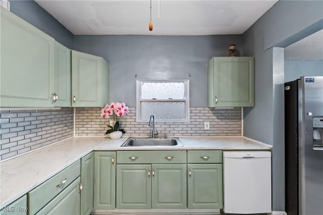 kitchen featuring sink, stainless steel fridge, white dishwasher, green cabinets, and backsplash