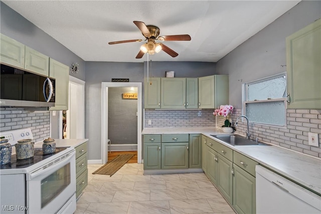 kitchen featuring sink, backsplash, white appliances, and green cabinetry