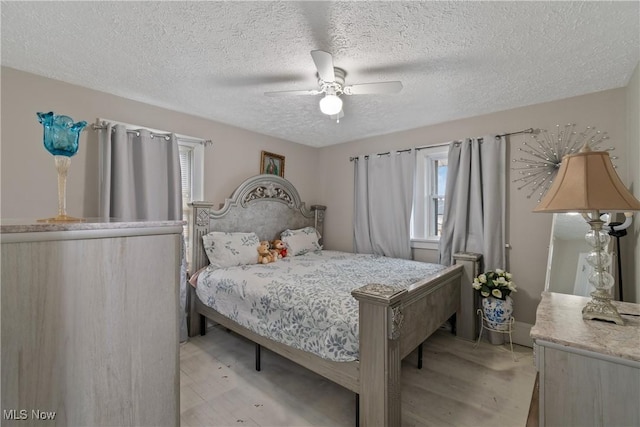 bedroom with a textured ceiling, light hardwood / wood-style floors, and ceiling fan