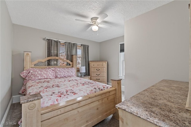 bedroom featuring ceiling fan, dark carpet, and a textured ceiling