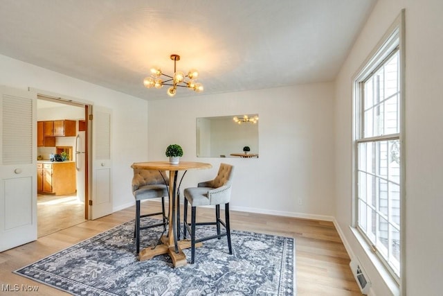 dining space with a chandelier, light wood-type flooring, and baseboards