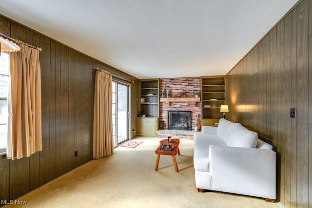 carpeted living room featuring a brick fireplace, built in shelves, and wood walls