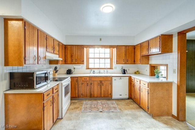 kitchen featuring brown cabinets, white appliances, under cabinet range hood, and light countertops