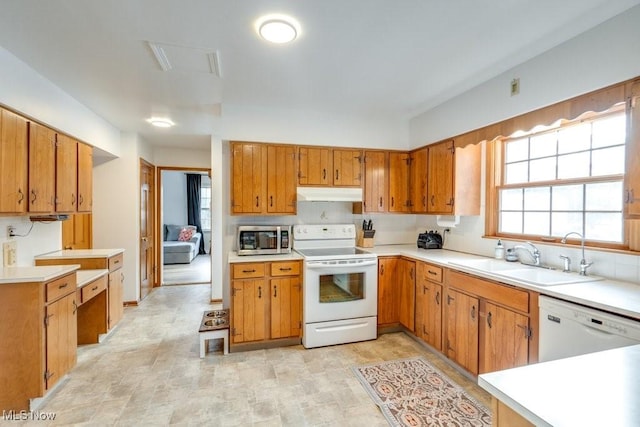 kitchen featuring white appliances, light countertops, a sink, and under cabinet range hood