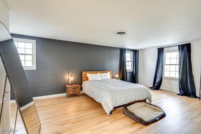 bedroom with light wood-style floors, baseboards, and visible vents