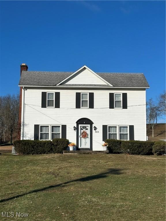 colonial-style house featuring a front lawn